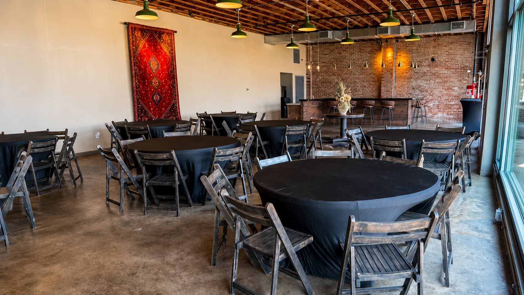 Full room set with round tables, black linens, and the bar in the background